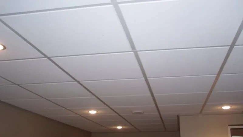 A finished suspended ceiling of smooth white tiles with recessed downlights